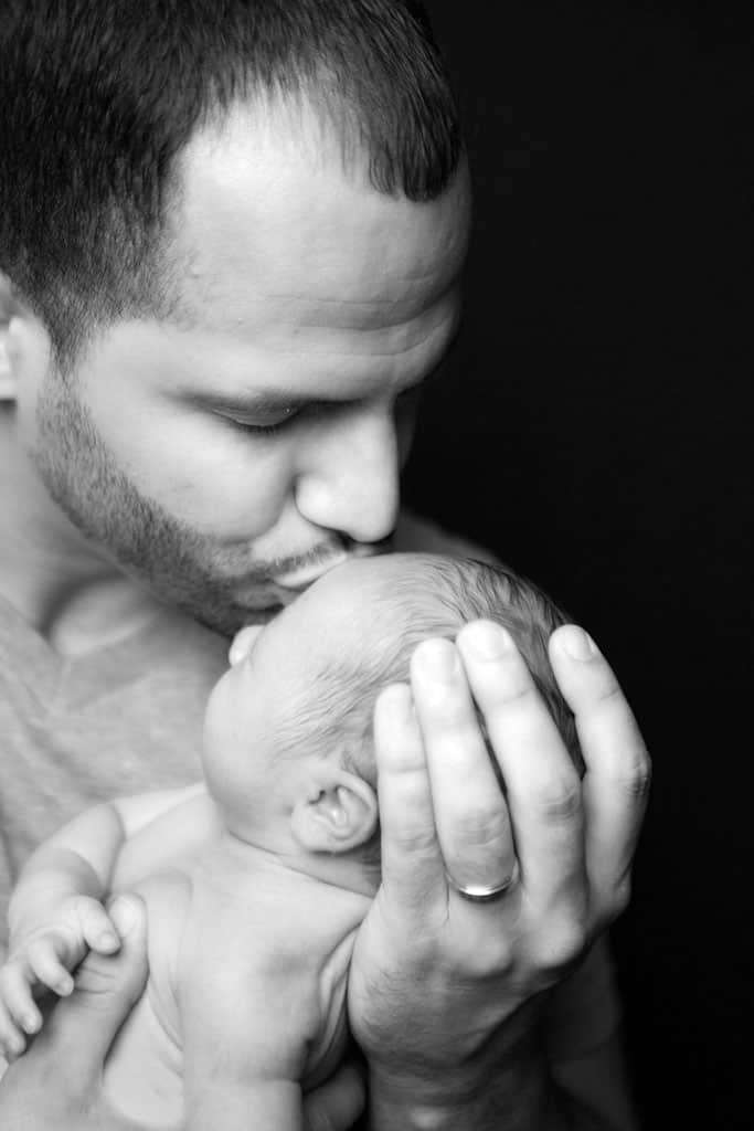father kissing newborn