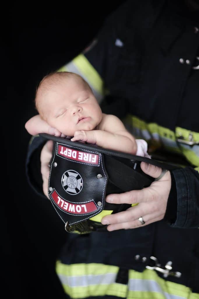 newborn girl in sleeping in firefighters hat