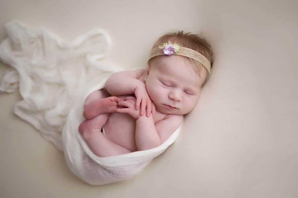 newborn curled up in wrap