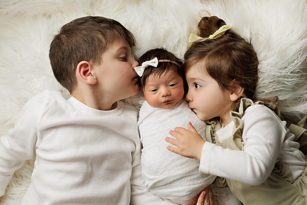 siblings kissing newborn