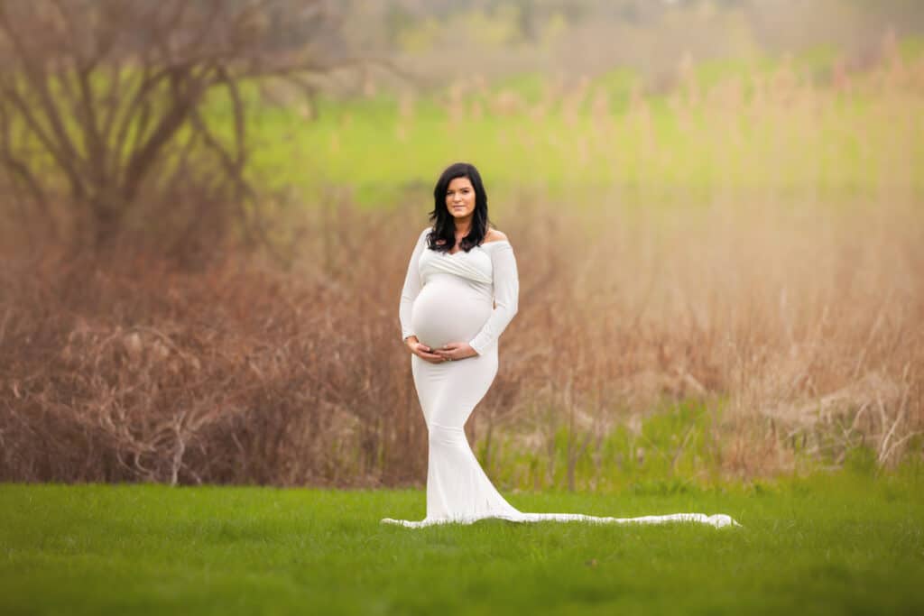 windham nh maternity portrait in white dress standing in grass field