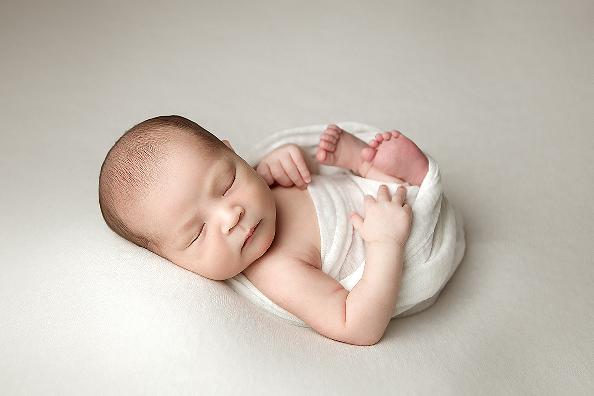 Boston Newborn Portrait of baby on white backdrop in white wrap in Womb pose