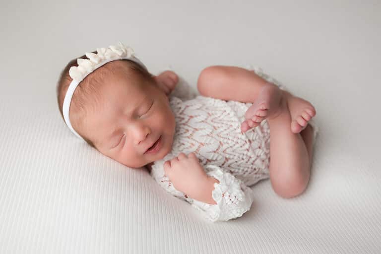 Newborn Portrait - Lace Romper with white bow headband.