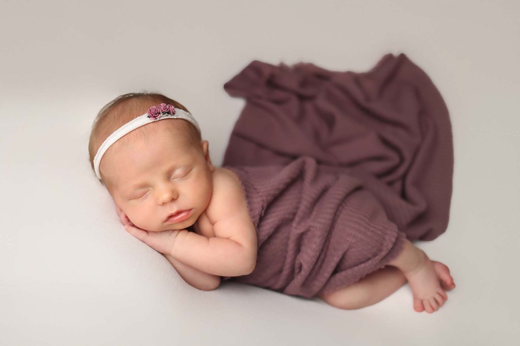 Salem NH Newborn Portrait of baby girl laying on her side with hands tucked under her cheek.