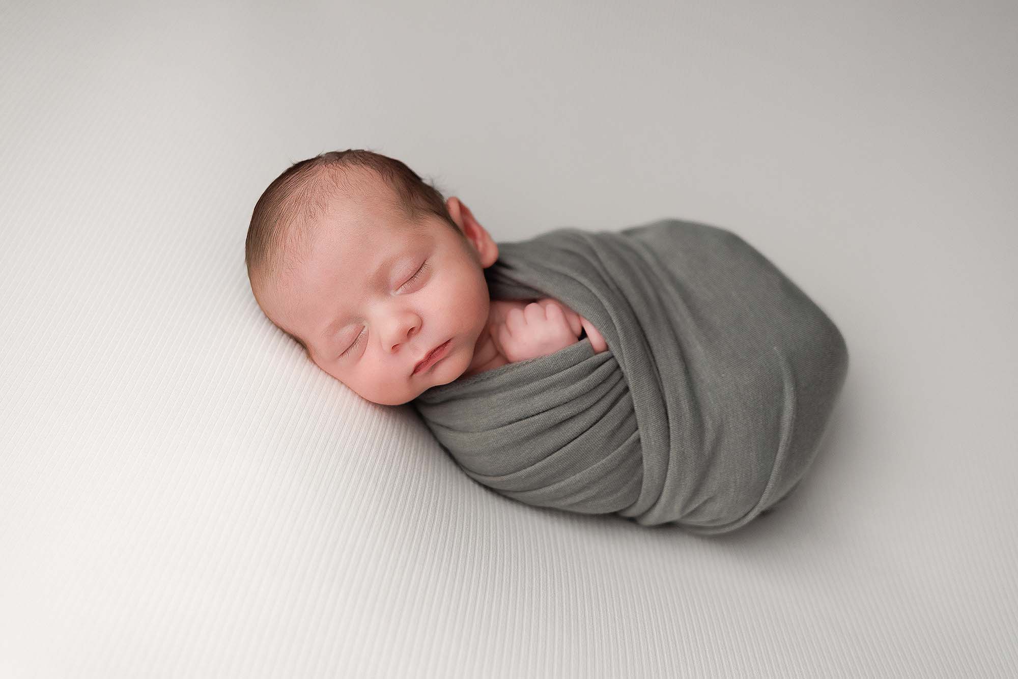 Andover MA newborn portrait of baby swaddled in a sage green wrap.