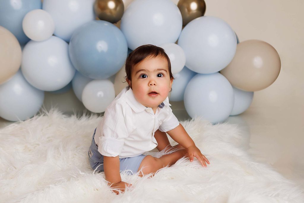 One Year Cake smash session of little boy sitting and looking at camera.