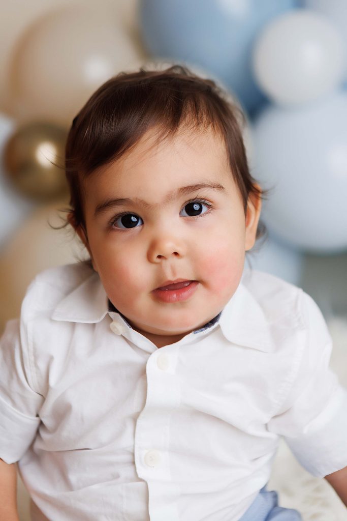 One Year Old Cake Smash Session of little boy smiling at camera.