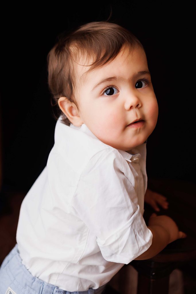 One year old turning to look at the camera for a cake smash portrait.