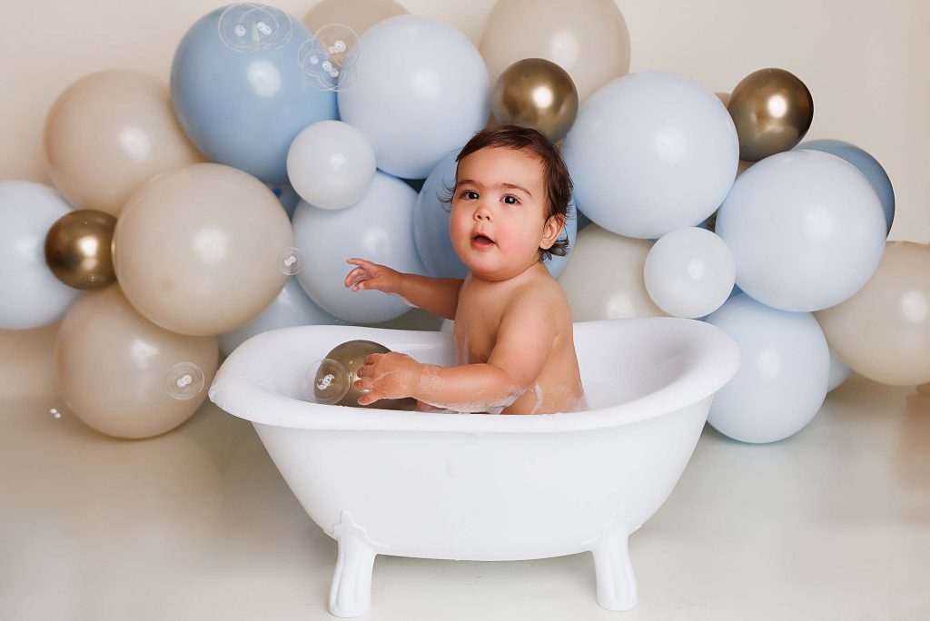 One year old splashing in tub for a cake smash session.