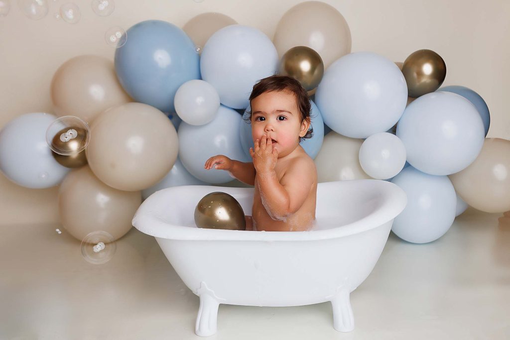 One year old in tub for a bubble bath for a cake smash session.