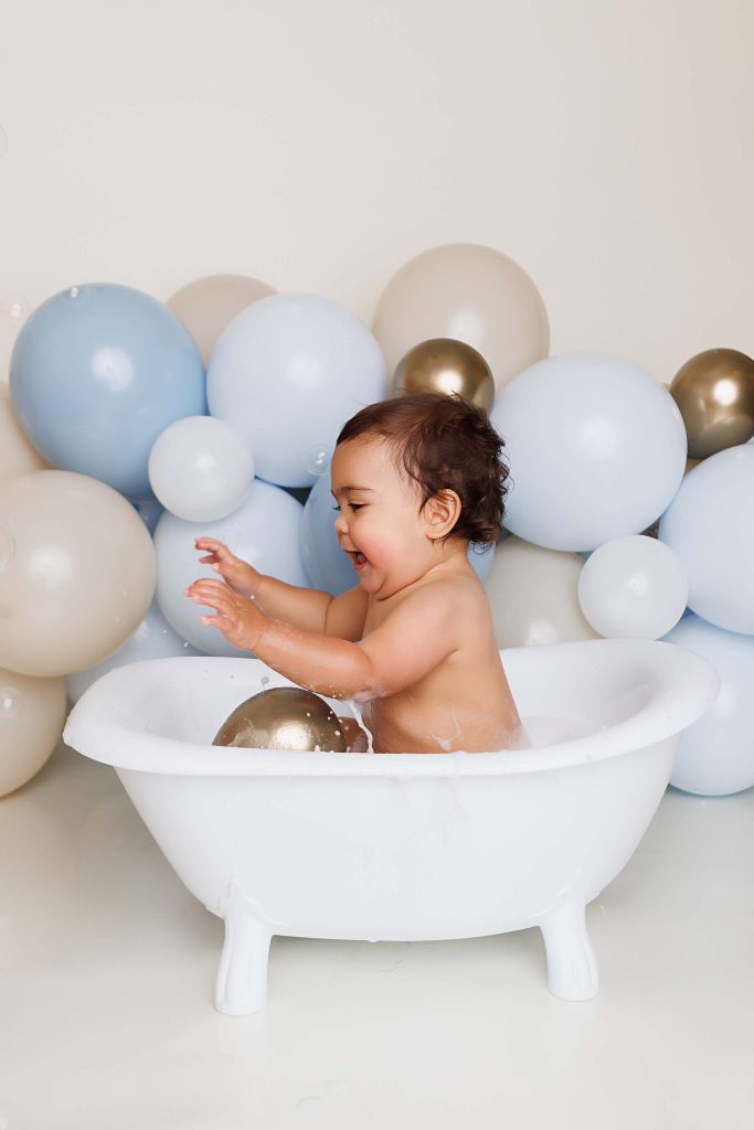 One Year old boy splashing in tubby for his cake smash portrait session.