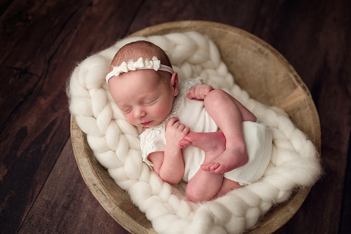 Salem NH Newborn Portrait of baby girl in an ivory outfit laying in a wooden bowl.