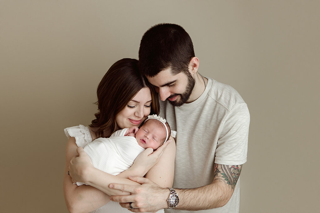 Salem NH Newborn Portrait session of baby girl in the arms of her mother and father.