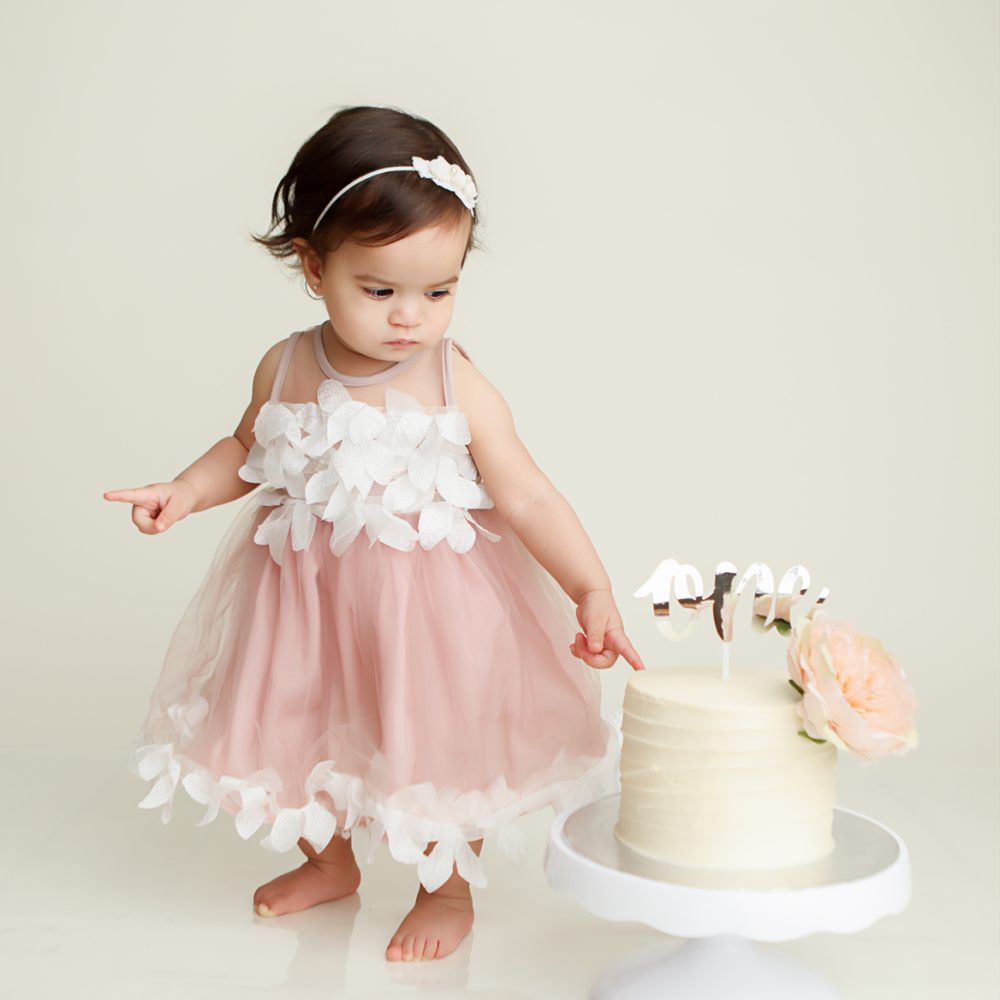 NH Cake Smash Session of little girl touching cake.