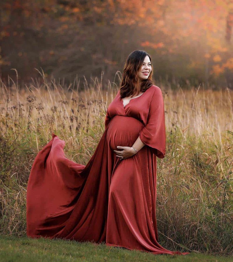 Boston Maternity Photographer. Portrait of expectant mother in rust colored dress in front of fall foliage.