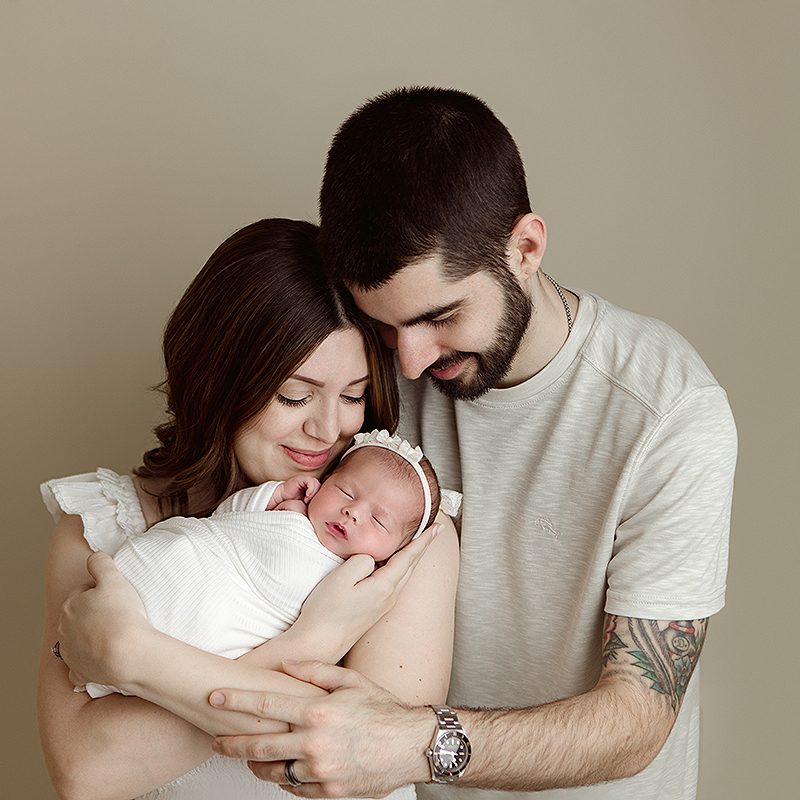 Salem NH Newborn Portrait session of baby girl in the arms of her mother and father.