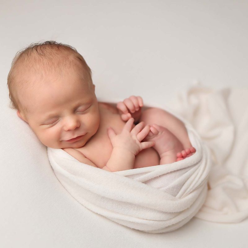 NH Newborn Portrait of baby girl all cozy in a soft white swaddle wrap.