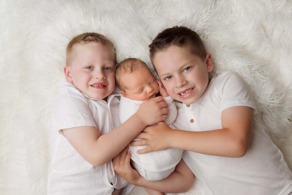 Windham NH Newborn Portrait of brothers snuggling with their new baby brother.