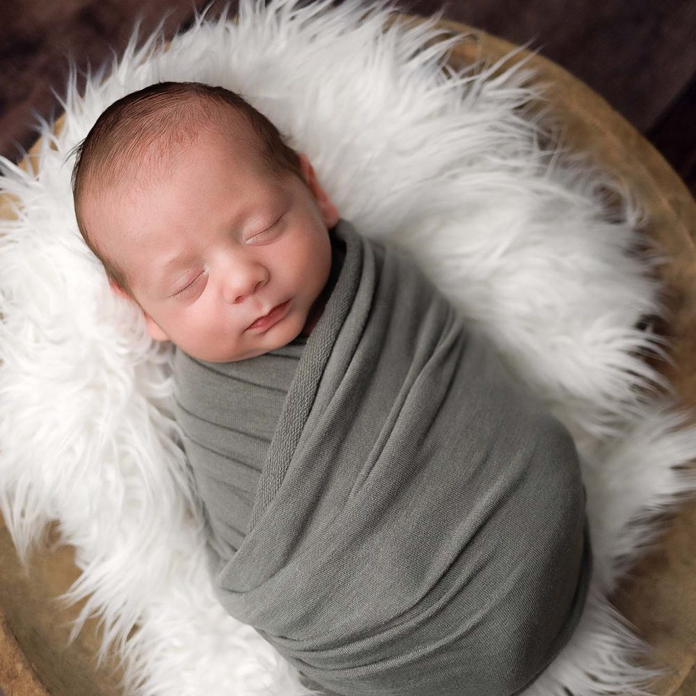 Andover, MA newborn portrait of baby boy wrapped in a sage green wrap sleeping in a wooden bowl.