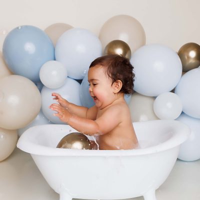 One Year old boy splashing in tubby for his cake smash portrait session.