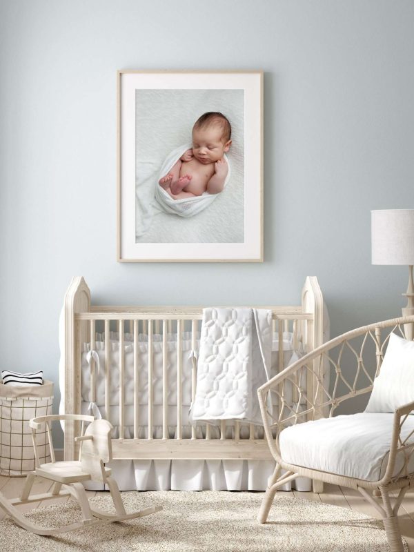 Newborn Nursery with ivory furniture and framed newborn portrait on the wall.